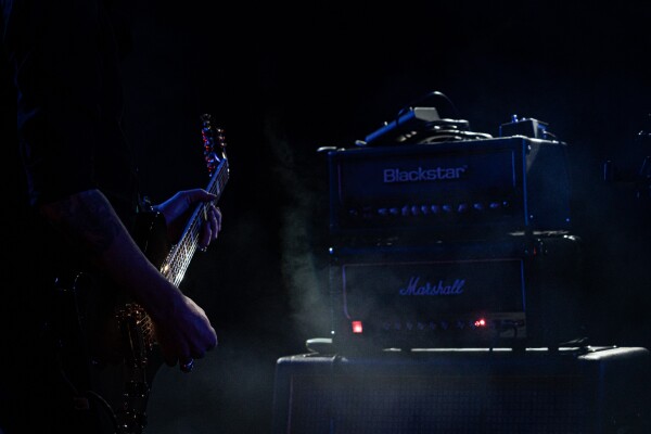 A guitar being played, Amps stacked on top of each other.